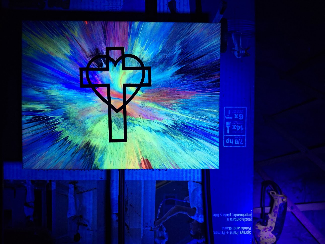 Colorful abstract design with a cross-like symbol on a screen in a dark room.