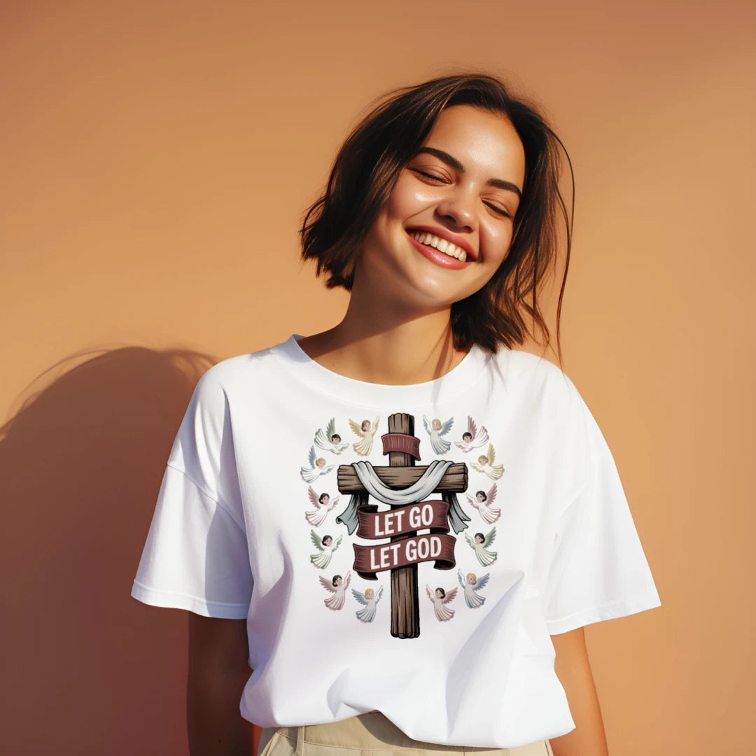 “Divine Faith Armor™ ‘Let Go Let God’ Christian shirt featuring wooden cross with draped cloth, surrounded by colorful angels in radiant light.”