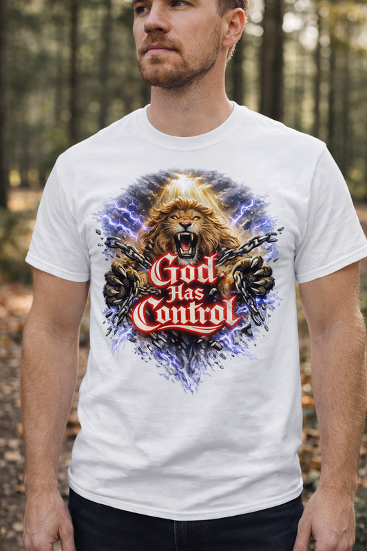 Man wearing a white t-shirt with a graphic design of a lion and 'God Has Control' text in a forest setting.