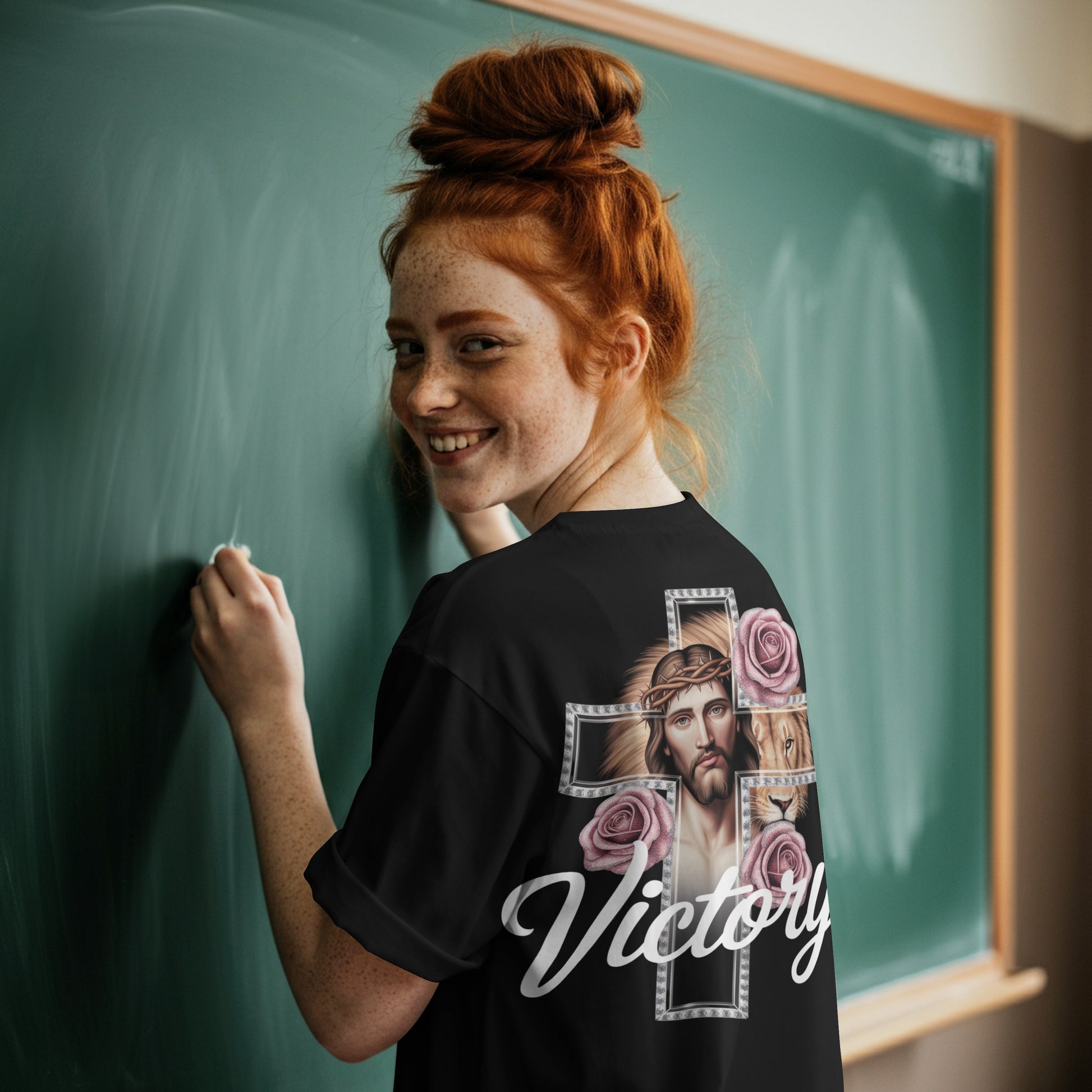 Divine Faith Armor™ Victory T-Shirt featuring a mirrored image of Jesus in a glass cross, a majestic lion, and sparkling roses, faith-inspired Christian apparelPerson wearing a black t-shirt with a design and the word 'Victory' in front of a green chalkboard.